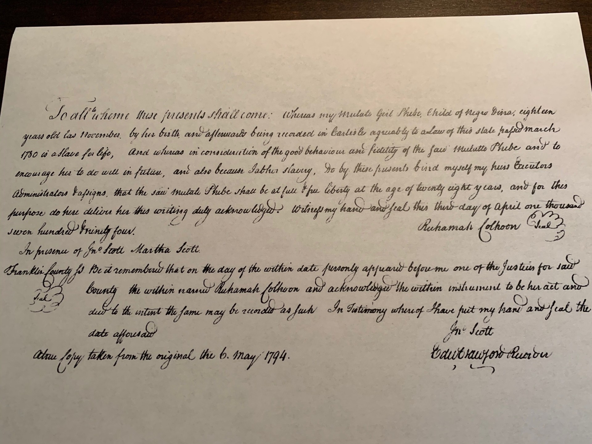 A copy of an official-looking, hand-written government document. The paper is bright white and the cursive script dark and spindly. In it, Ruhamah Colhoon vows to manumit a woman she identifies as “Mulatto Phebe” when she turned twenty-eight. Ruhamah declares that she does this because of Phebe’s “good behaviour and fidelity,” to “encourage her to do well in future,” and because Ruhamah “abhor[s] slavery.” 